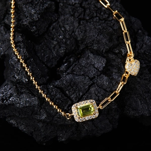 Macro shot of s925 silver bracelet with emerald cut green gem and heart charm