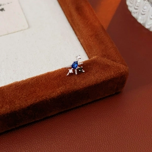 Macro detail of silver star stud earring with blue pear-cut gemstone and cubic zirconia