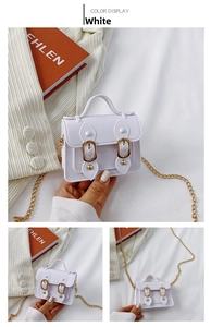 Detailed view of white mini Cambridge bag with golden chain and magnetic buckle strap