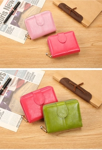 Close-up of colorful short zip wallets in pink and green on a vintage wooden desk