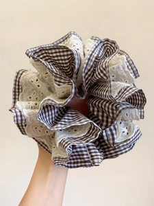 Detail of oversized scrunchie with brown houndstooth fabric and white floral lace textures