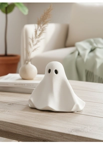 Detail van een wit keramisch spookfiguurtje met matte afwerking op een houten tafel