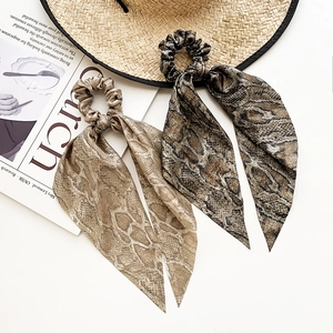 Chic snakeskin print hair scrunchies with long streamers on a stylish flat lay background