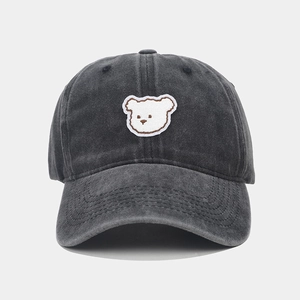 Close-up of a dark gray washed denim baseball cap with a cute white bear embroidery