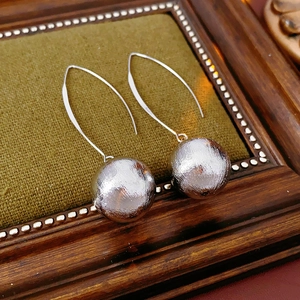 Détails macro de boucles d'oreilles boules argentées brossées avec longs crochets