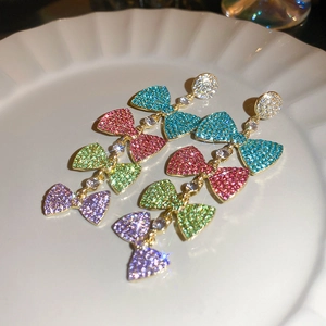 Close-up of sparkling colorful rhinestone bow tassel earrings on white display