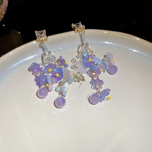 Detail of purple flower resin earrings with geometric beads and square zircon studs