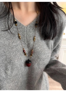 Close-up of a vintage acorn pendant necklace with wooden beads on a grey sweater