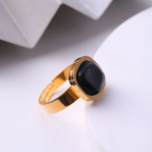 Gros plan d'une bague réglable dorée avec une pierre noire carrée sur un support blanc