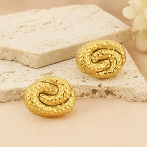 Detailed macro view of 18k gold plated spiral earrings with a hammered textured surface