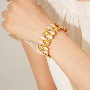 Close-up of vintage gold bracelet with zircon drops and white enamel on a wrist
