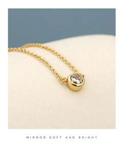 Macro detail of round cubic zirconia pendant on a minimalist golden link chain
