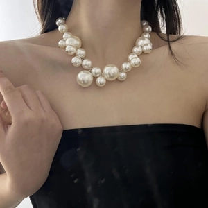 Close-up of bohemian layered pearl necklace featuring varied bead sizes on a female model