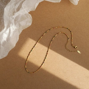 Macro shot of 18K gold plated rainbow necklace with colorful beads and K18 engraving detail