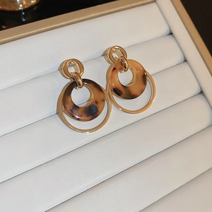 Detailed close-up of gold-plated metal and amber resin double hoop earrings on tray