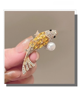 Macro shot of koi fish brooch with yellow crystals and a large white pearl detail