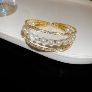 Macro shot of multi-layer gold bangle with white pearls and sparkling pavé crystals