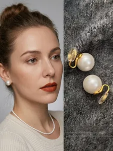 Detail of elegant white acrylic pearl earrings with golden clips and silicone pads