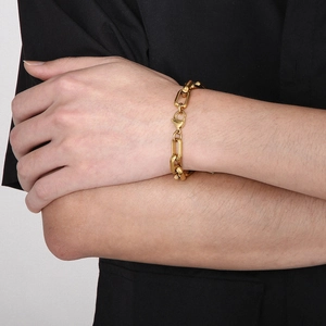 Close-up of a masculine gold chain bracelet with geometric edges worn on a wrist