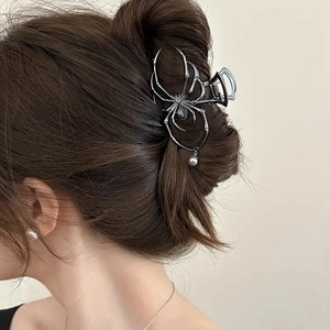 Silver spider hair claw with pearl tassel pendant worn by model from a side-back angle view
