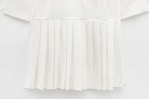 Close-up of white pleated dress hem showing high-quality twill fabric texture
