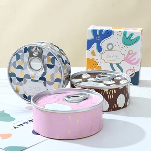 Detailed view of tin candles with geometric patterns and branded gift box packaging