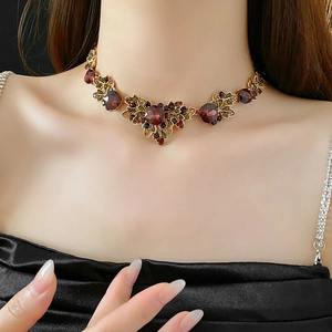 Detail of vintage necklace with red gemstone and gold leaf accents on a model neckline