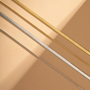 Flat herringbone and round snake chains in gold and silver finishes with sharp shadows