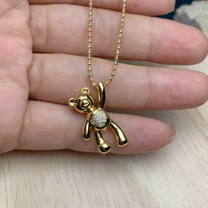Detailed view of a golden bear pendant with sparkling zircons held by a hand