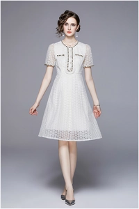 Close-up of white lace dress featuring black ribbon edges and elegant pearl buttons
