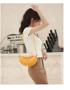 Close-up of yellow crocodile texture leather crescent bag with golden metal zipper detail
