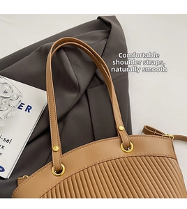 Detail of camel pleated tote bag showing metallic ring connection and fine leather strap