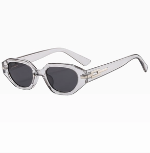 Close-up of cat-eye sunglasses with transparent grey frames and gold metal hinge details