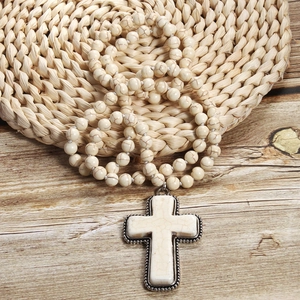 Detail of white marble beads and large cross pendant on natural woven wood surface