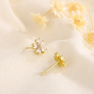 Macro shot of s925 gold flower studs with five drop-shaped zircons on burlap texture