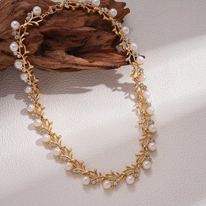 Detailed shot of golden branch necklace with pearls and rhinestones on wood backdrop