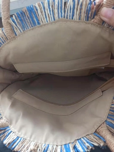 Interior view of straw beach bag showing beige lining and two zipper pockets