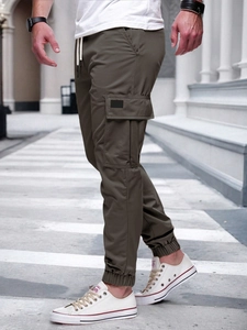 Detail view of olive cargo pants featuring drawstring waist and large flap pockets