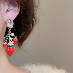 Close-up of strawberry drop earrings with red enamel and large oval crystal on model