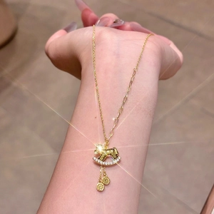 Golden rocking horse necklace with sparkling zircons and delicate charms on skin
