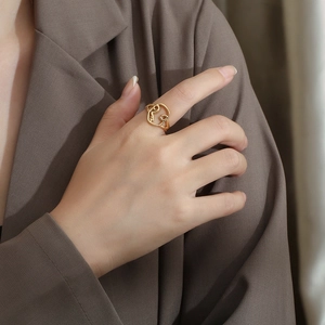 Artistic hollow face design gold ring on hand with elegant brown blazer background