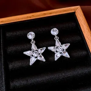 Elegant silver star drop earrings with sparkling cubic zirconia on a velvet display