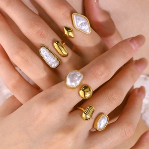 Close-up of elegant gold open rings with irregular baroque pearls worn on fingers