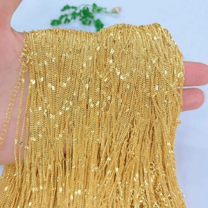 Close-up of numerous gold-plated copper necklaces showing fine textures and metallic shine