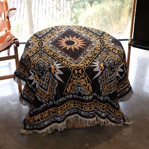 Macro detail of bohemian woven blanket featuring solar mandala pattern and colorful fringe
