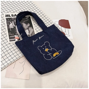 Detail of navy corduroy tote bag with bear embroidery and decorative ox charm