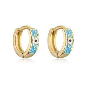 Detailed shot of golden hoop earrings featuring blue enamel evil eye patterns with zircons