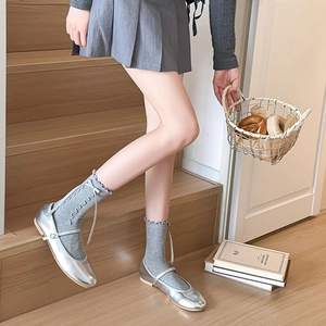 Detail of grey ruffle trim crew socks paired with silver metallic Mary Jane flat shoes