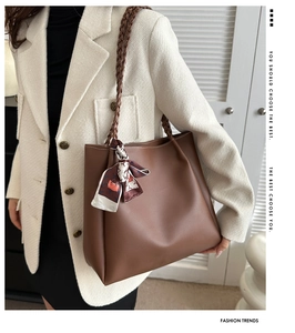 Detail of dark brown leather tote bag with silk scarf and woven shoulder strap