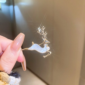 Détail d'une broche en forme de cerf doré avec cristaux scintillants et perle blanche